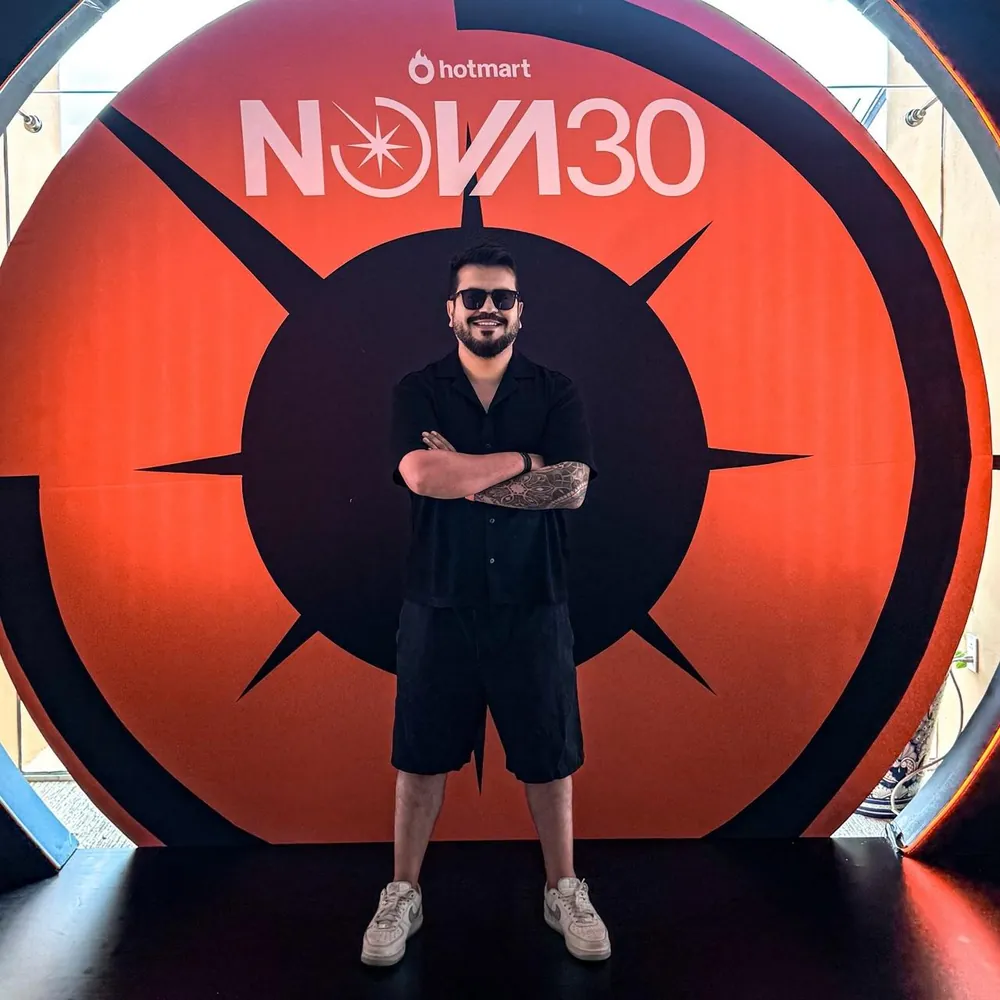 Andreti de pie con los brazos cruzados frente al escenario de Hotmart NOVA30